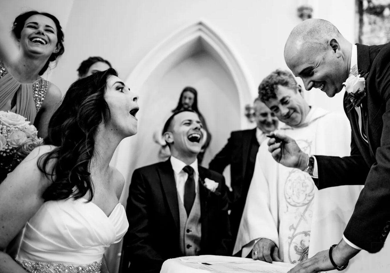 Bride and groom and wedding guests laughing black and white image