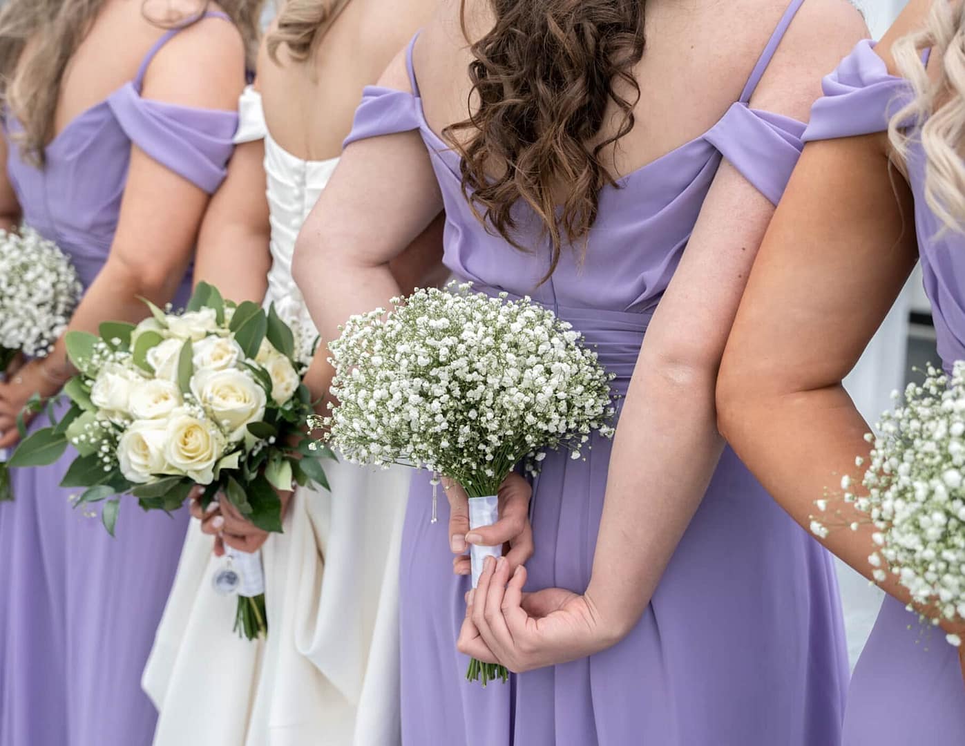 Bridesmaids in lavender dresses holding bouquets at shendley cricket club