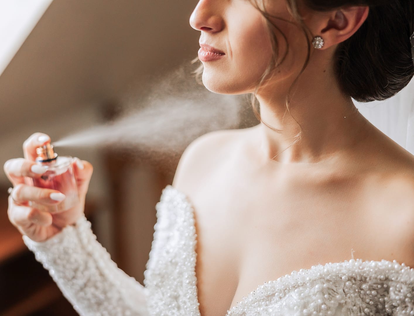 Bride applying perfume before ceremony at ashridge house hertfordshire
