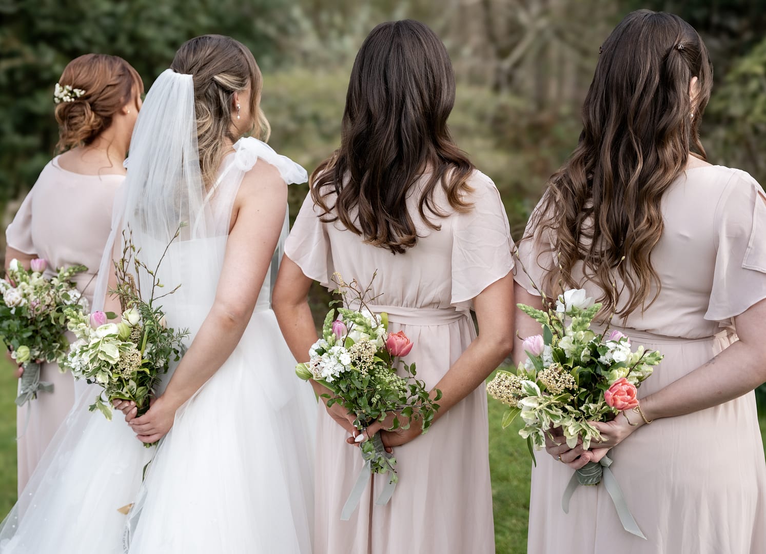Bridesmaids holding flowers, facing away.