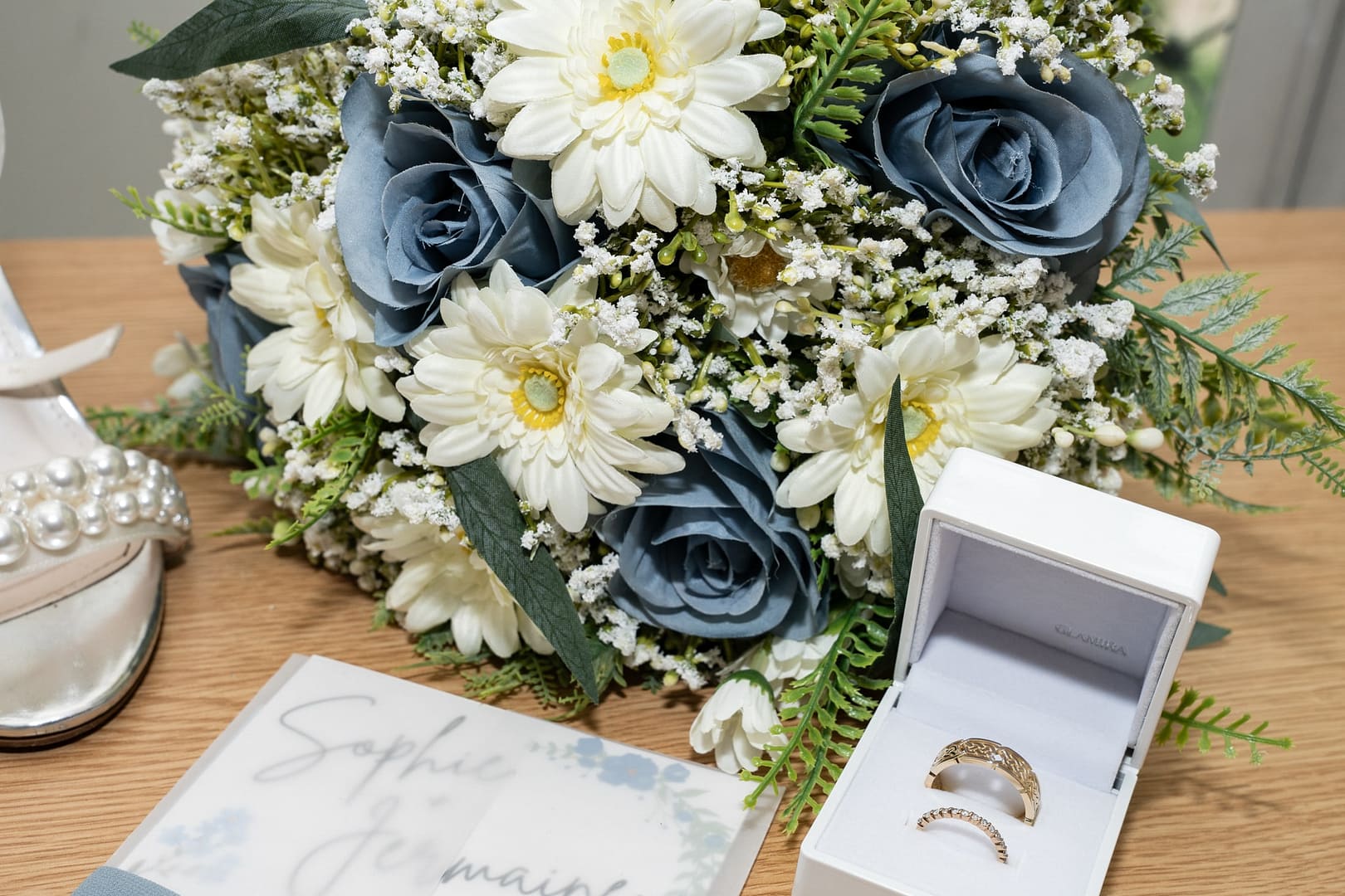 blue and white bridal bouquet with wedding rings inn white box