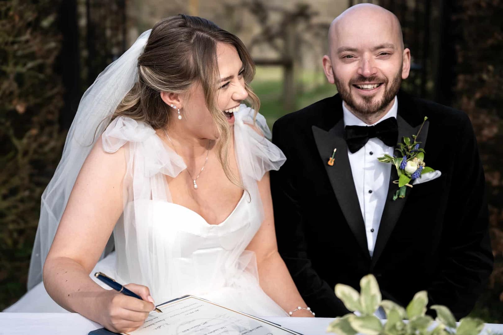 bride and groom signing registrar bride laughing