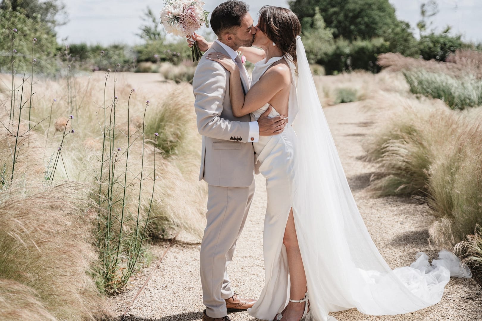 bride and groom kissing in field